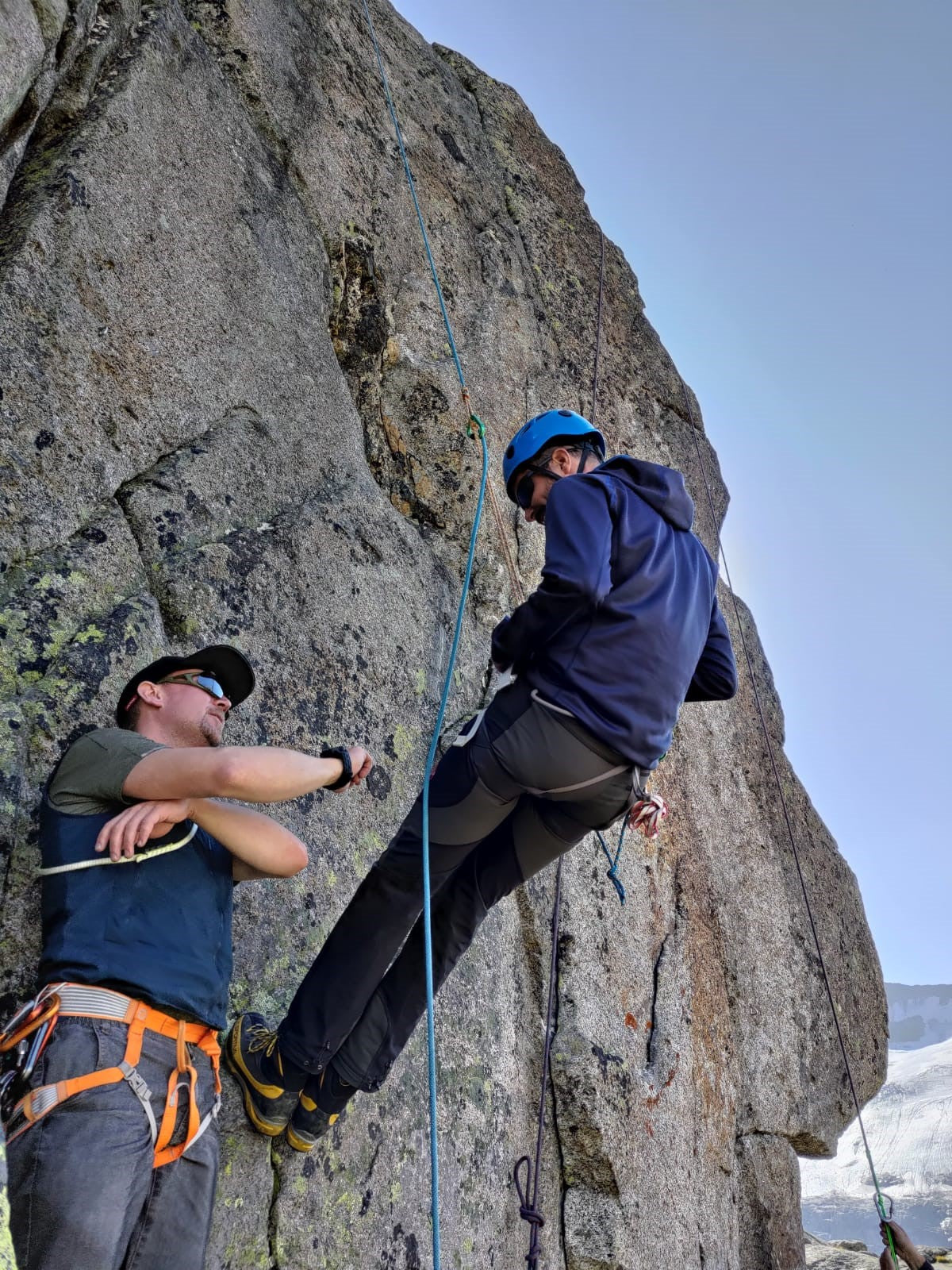 Mann beim Prusiken im Fels und Bergführer erklärt die Vorgehensweise.